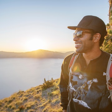 TTNK3J Smiling hiker standing on mountain at Crater Lake National Park during sunset