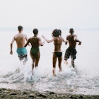 A group of teenagers play in and around the salt water of the Puget Sound, an inlet of the Pacific Ocean in Washington state, in the United States.  They splash into the cool water.