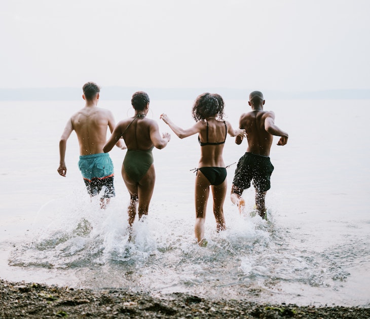 A group of teenagers play in and around the salt water of the Puget Sound, an inlet of the Pacific Ocean in Washington state, in the United States. They splash into the cool water.