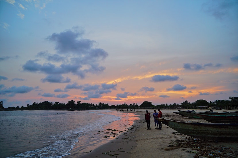 Late sunset / dusk in Tarkwa Bay beach (Lagos). Some men are standing at the beach. There are boats on the sand.