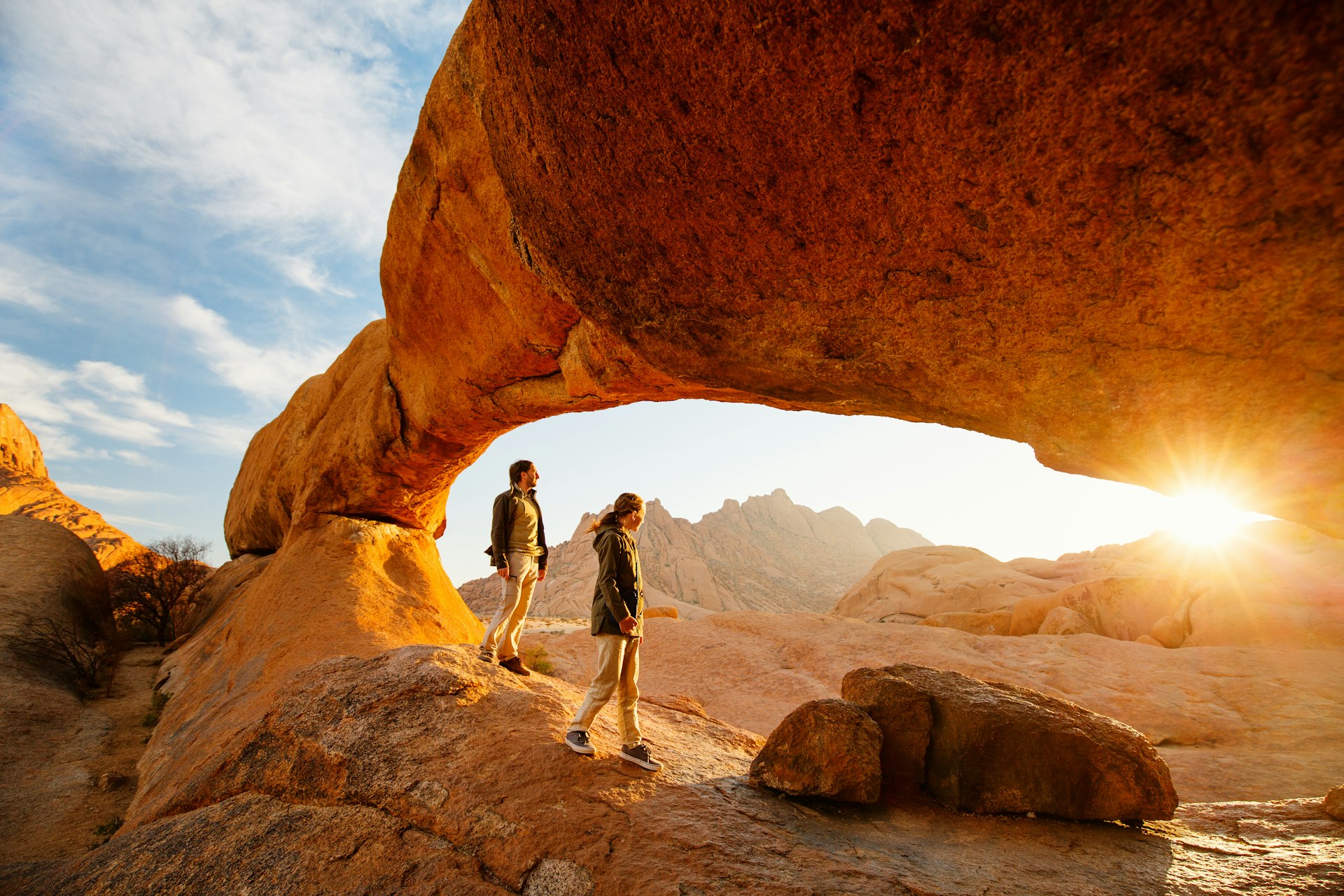 Family father and daughter enjoying sunrise in Spitzkoppe area with picturesque stone arches and unique rock formations in Damaraland Namibia