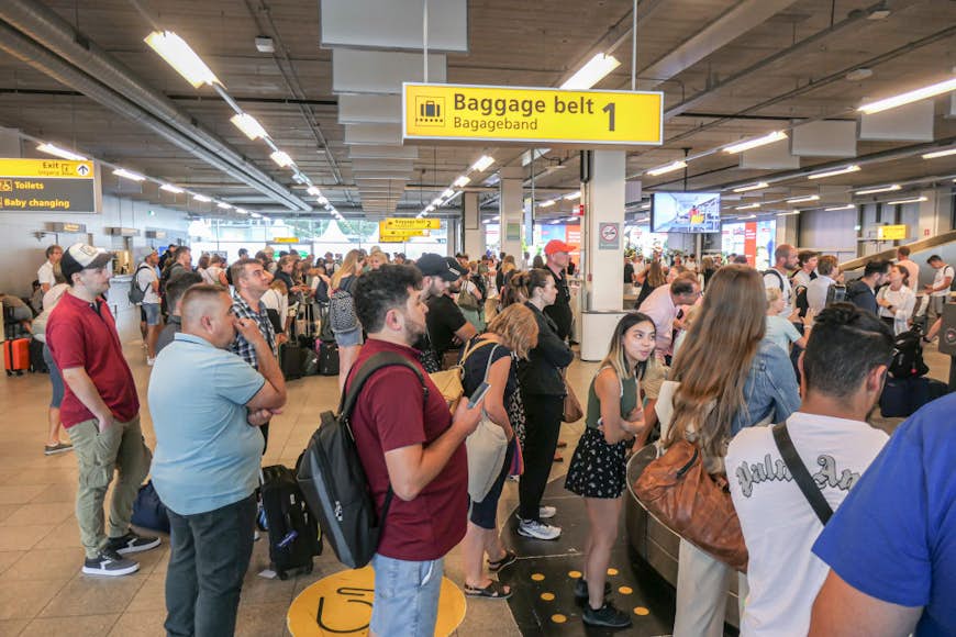 Passengers wait for their luggage at the arrivals baggage belt area of Eindhoven airport
