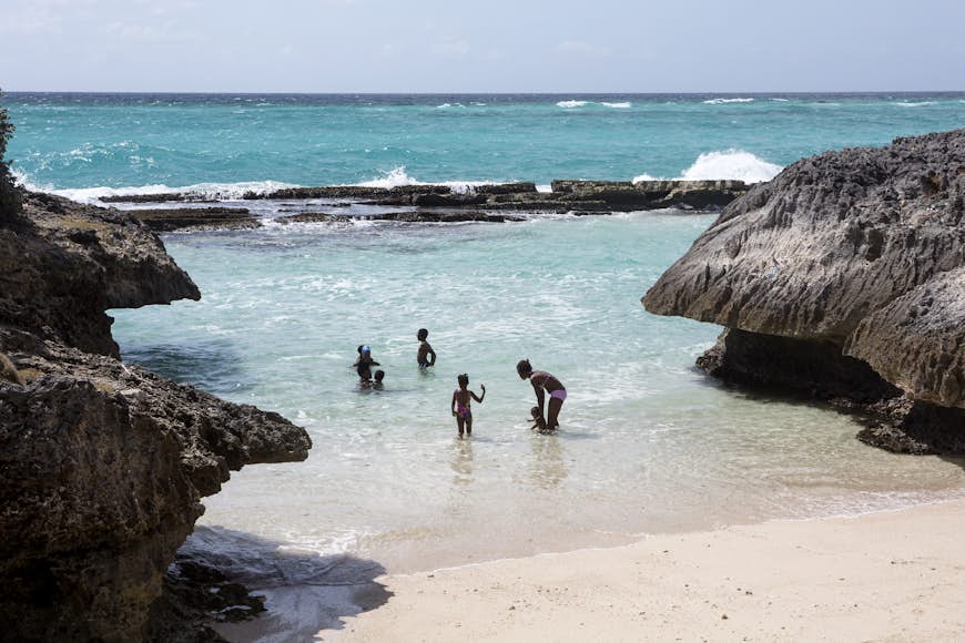 En lokal familj njuter av en stund i havet vid Shark Hole, Barbados