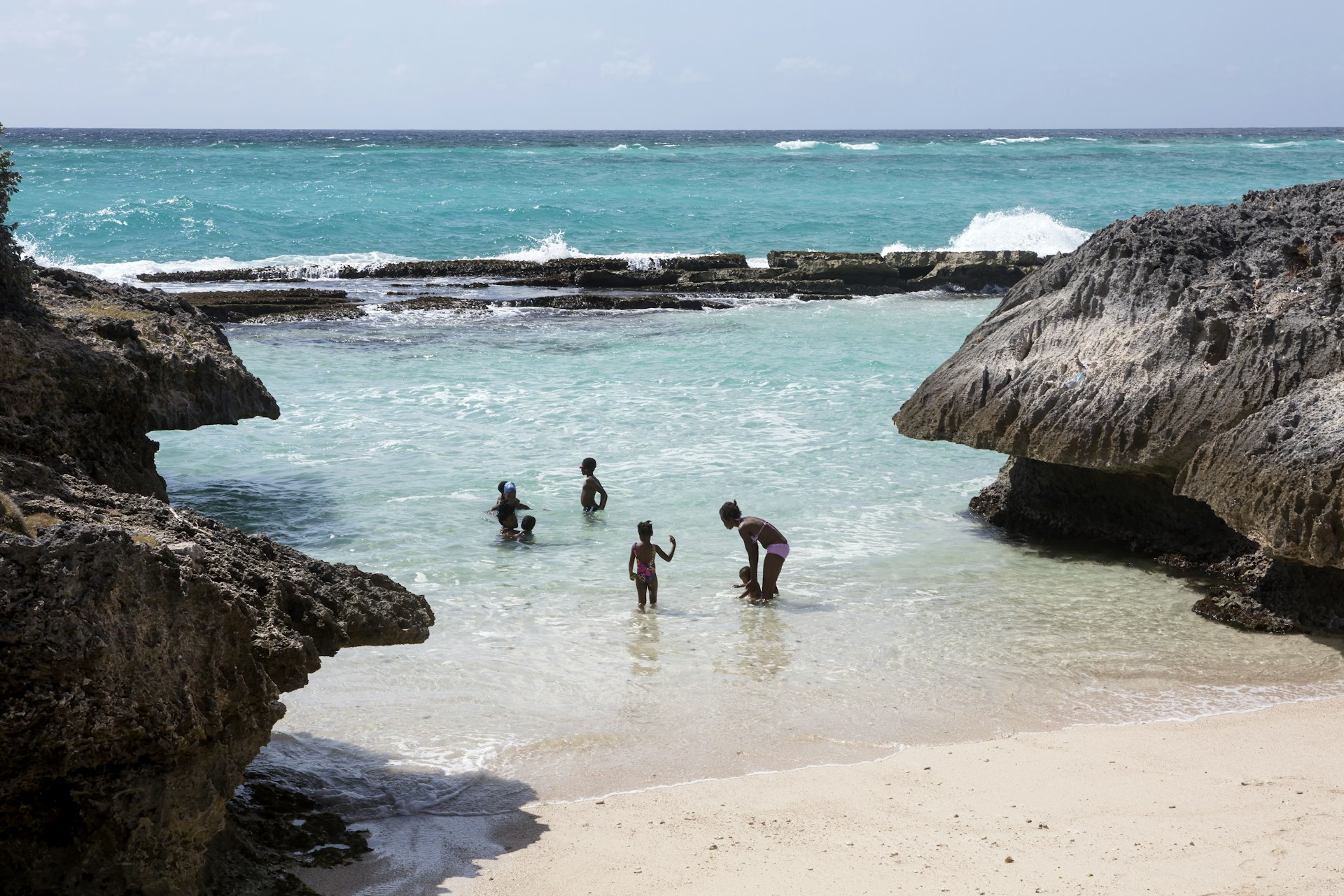 A local family enjoy some time in the sea at Shark Hole, Barbados