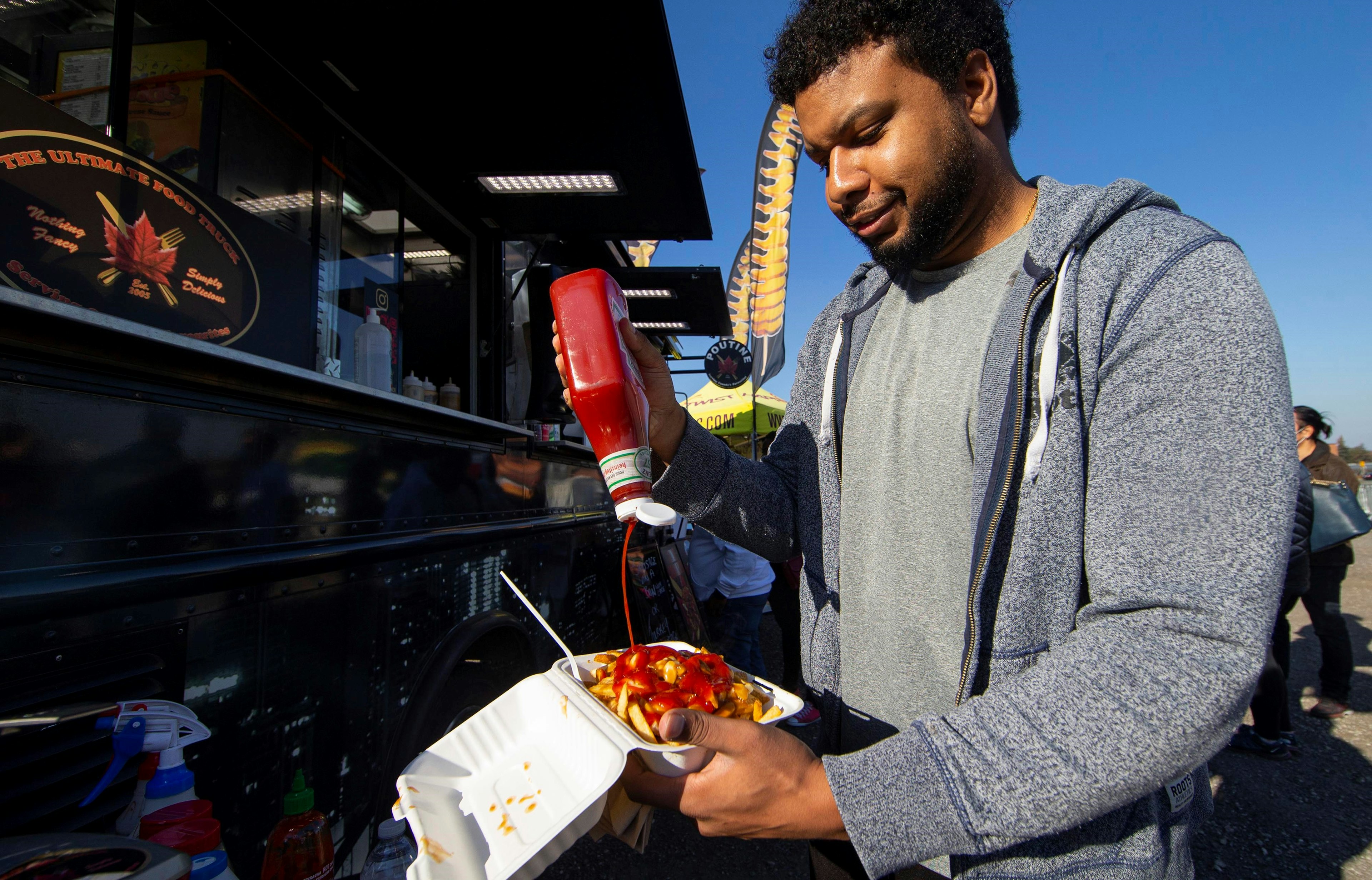 A customer puts some ketchup on his poutine at the Toronto Poutine Festival in Toronto, Canada.