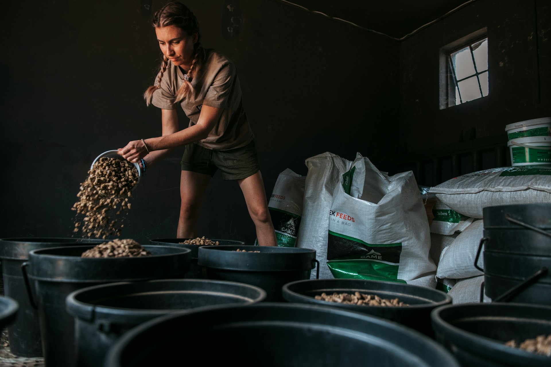 A conservationist pours feed into large black containers 