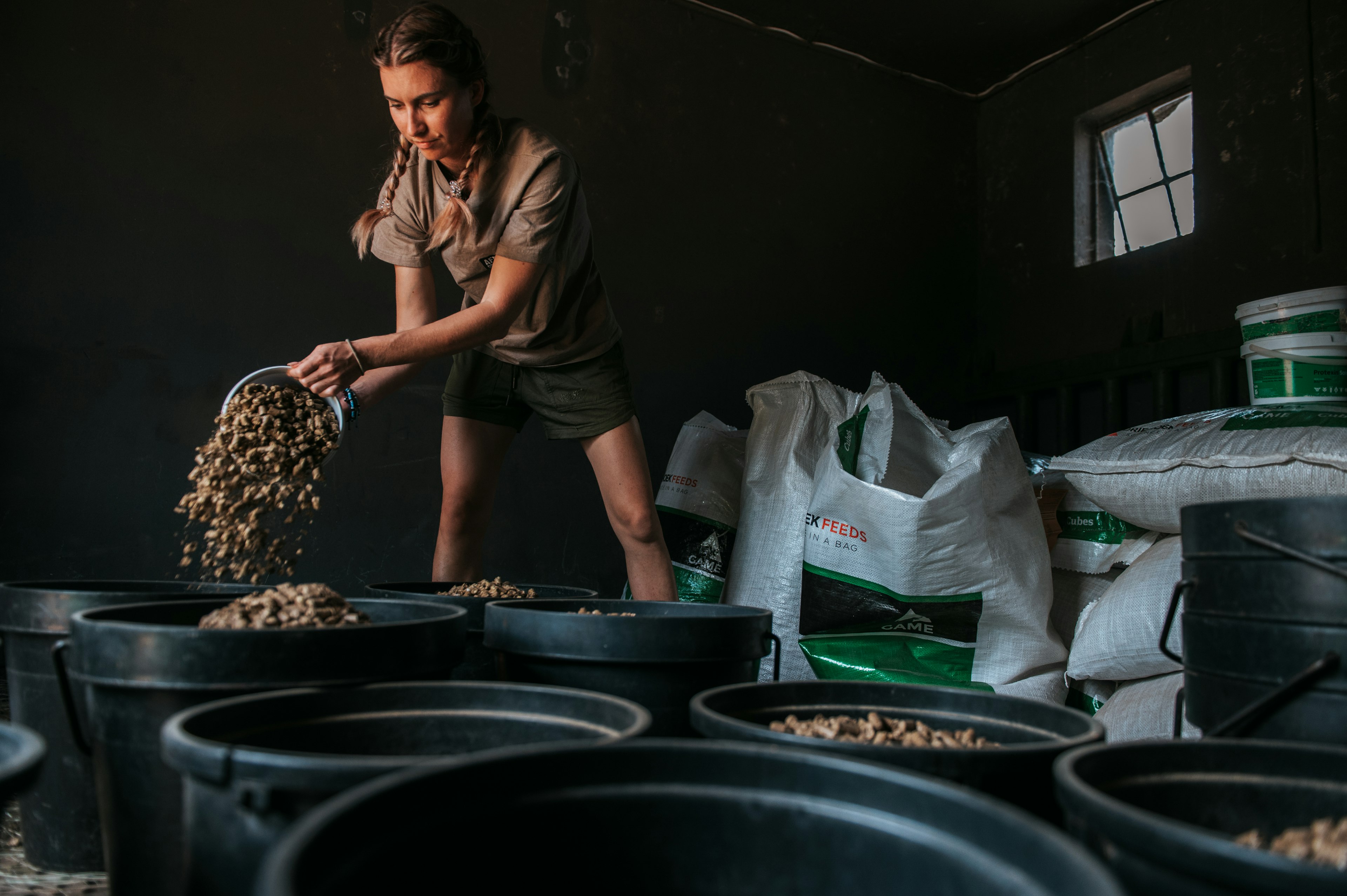 A conservationist pours feed into large black containers