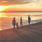 family enjoying sunset stroll on beach