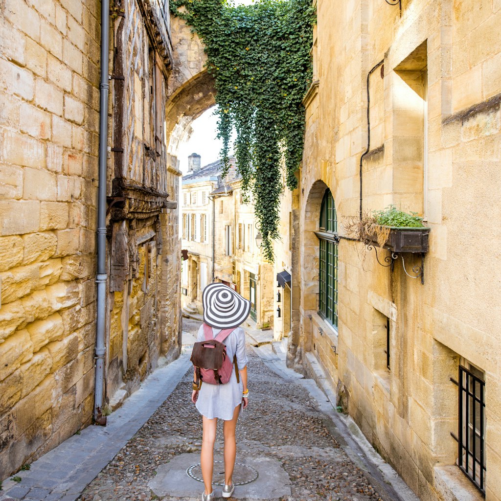 Young woman tourist walking old street at the famous Saint Emilion village in Bordeaux region in France