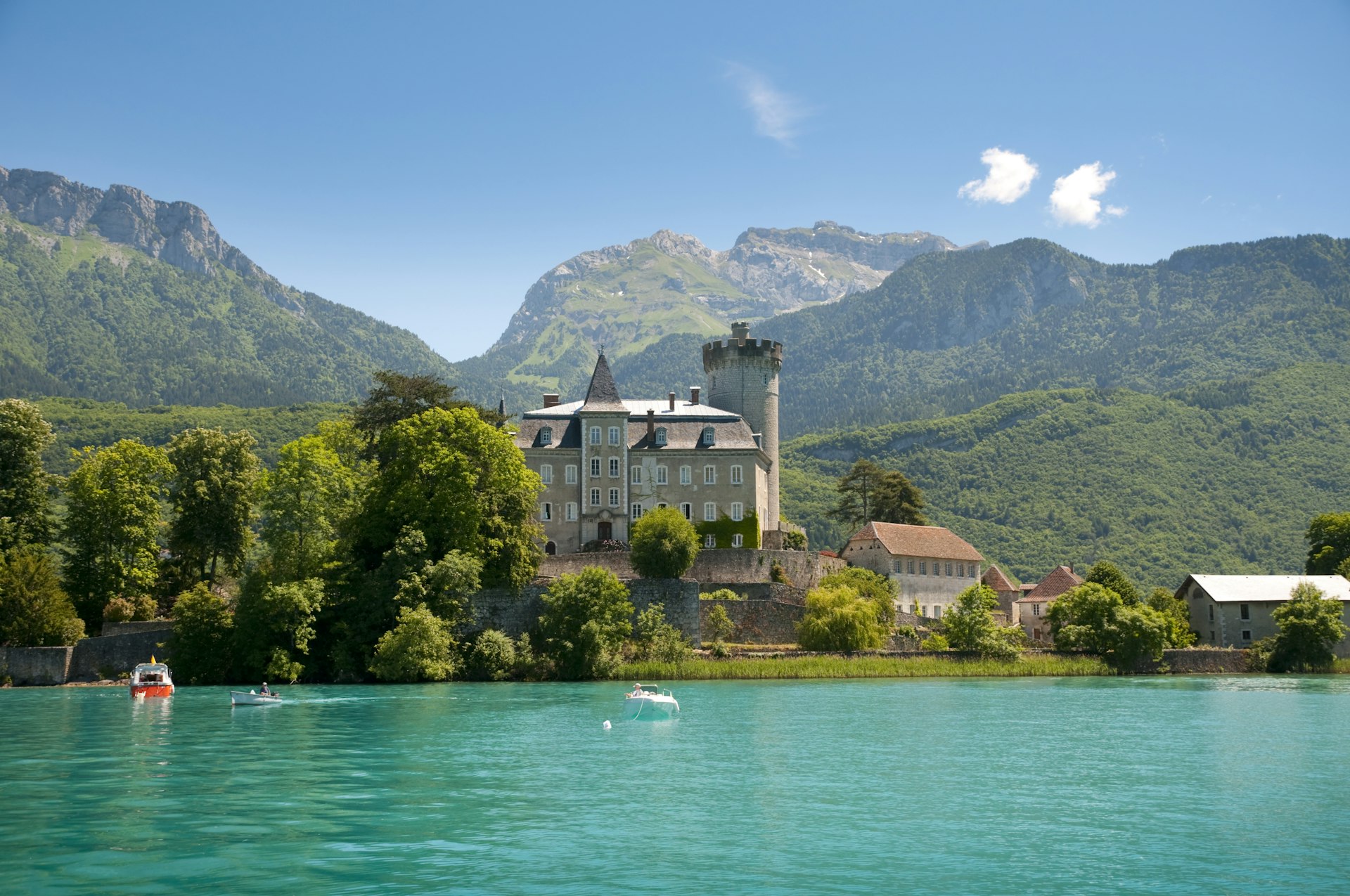 The Alpine Château d'Annecy overlooks a clear blue lake with the French Alps in the background