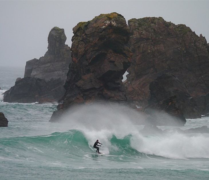 Unkown surfer surfing amongst rock stacks on the Isle of Lewis, West of Scotland.