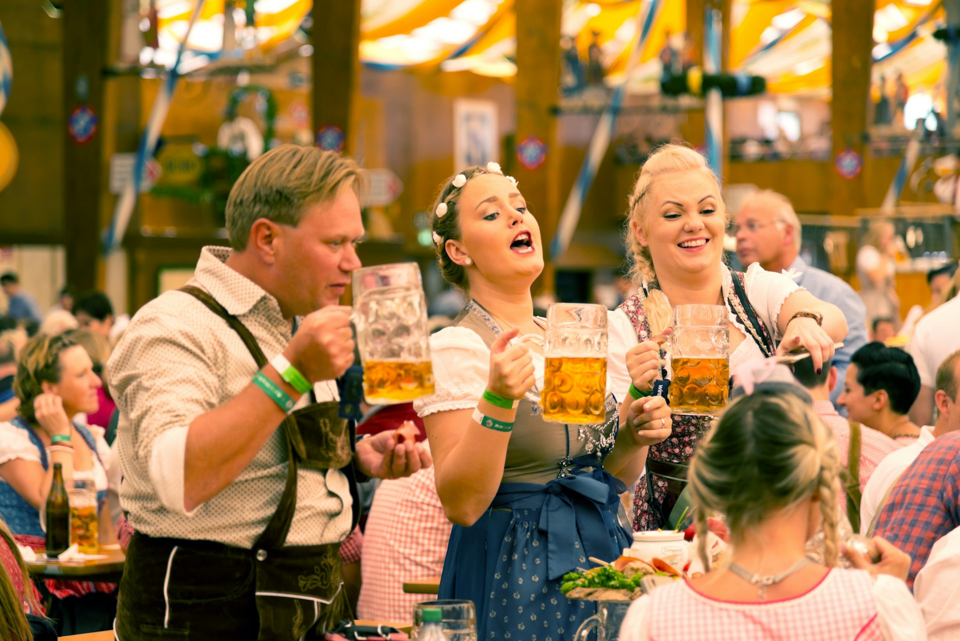 Two women and one man wear traditional Bavarian costumes during Oktoberfest