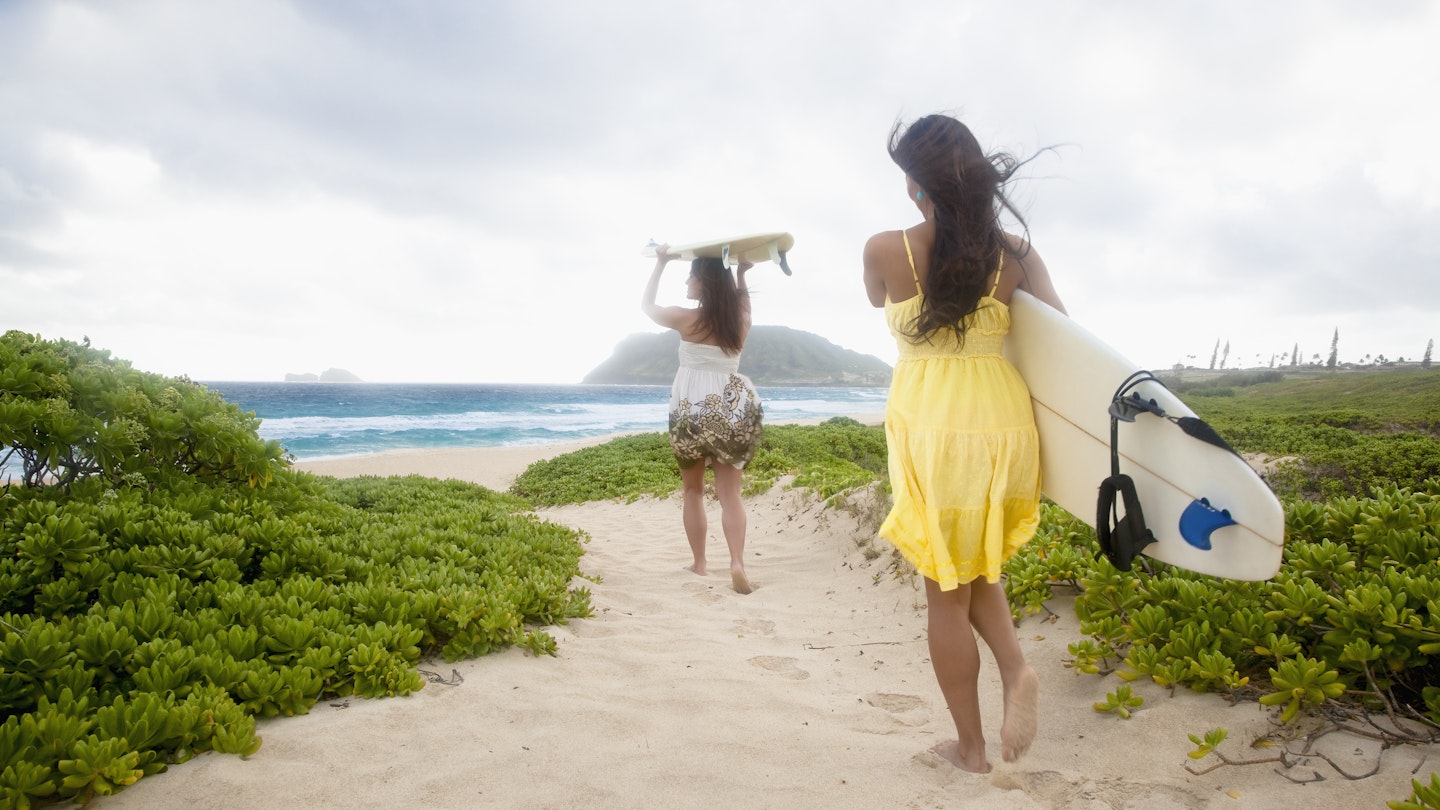 Women headed to the ocean to go surfing in Kailua, HI,