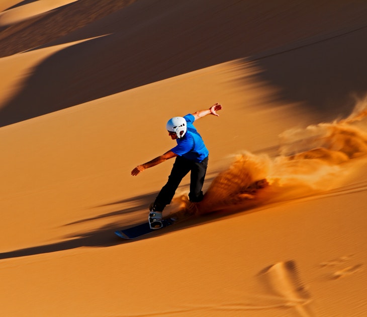 A trail of sand is visible in the late afternoon sun when this sandboarder speeds down the dunes of Swakopmund, Namibia.