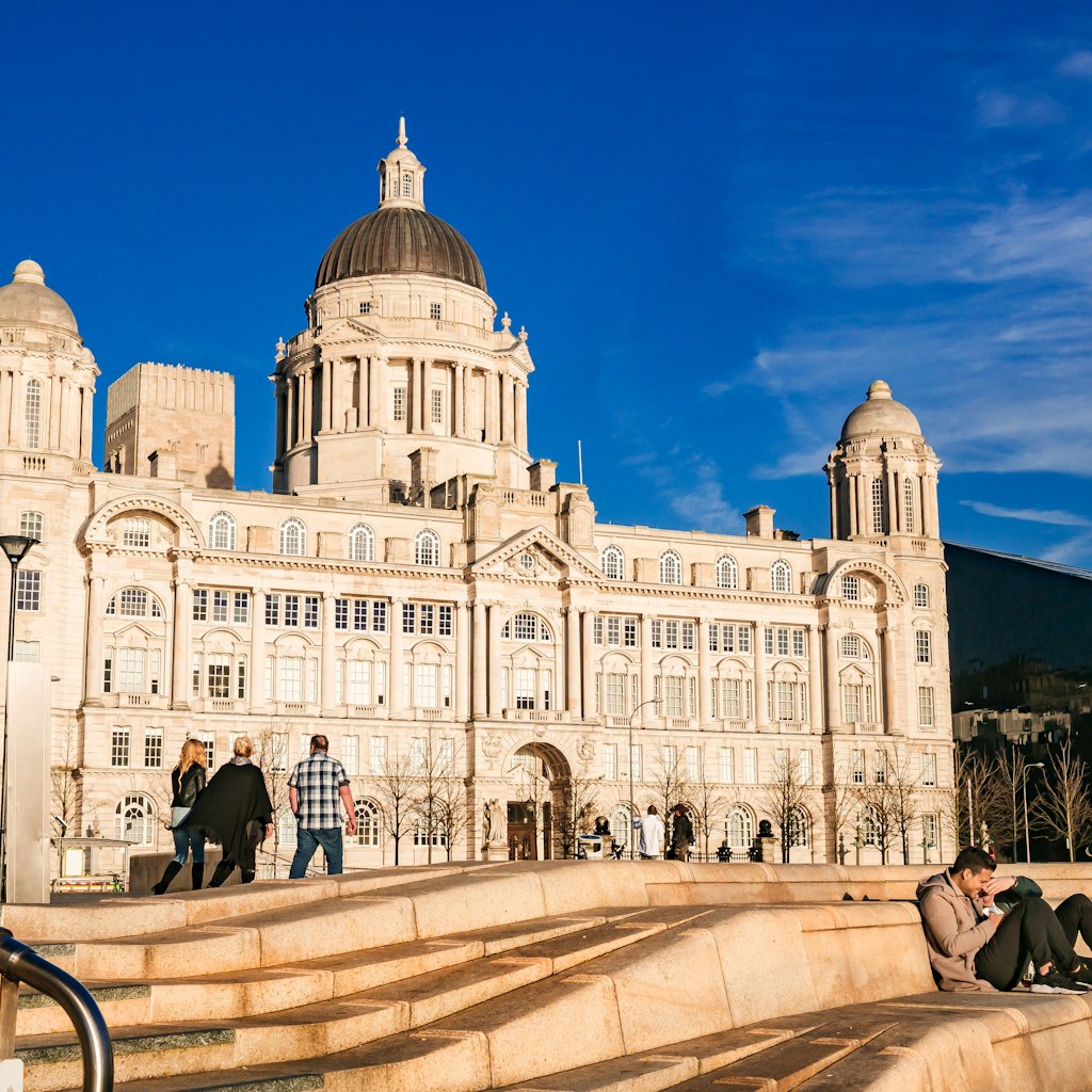 People walk past the famous Port of Liverpool building in the sunshine