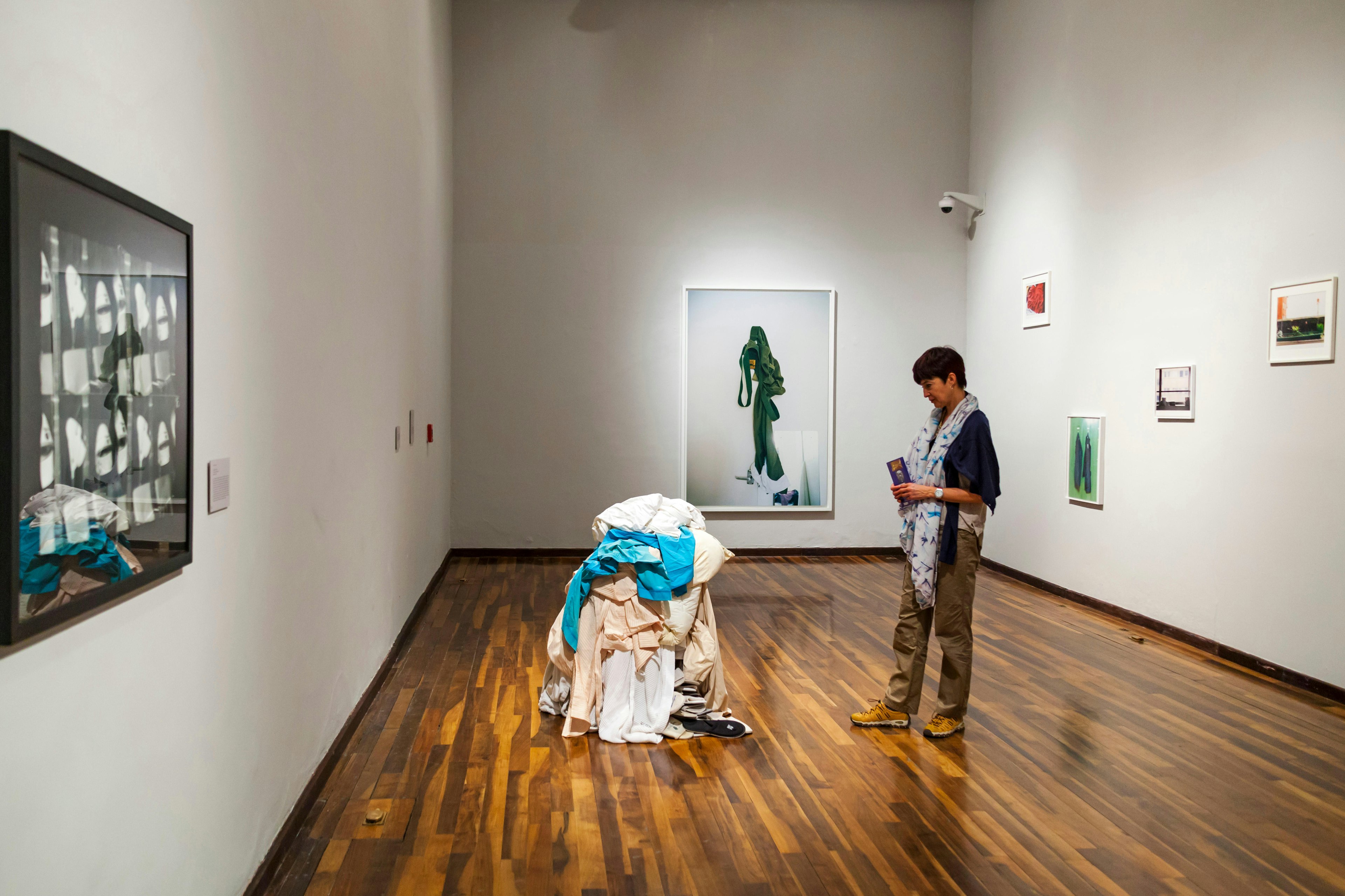 A person stands in front of a sculpture created from a pile of discarded clothes in a museum gallery in Guadalajara