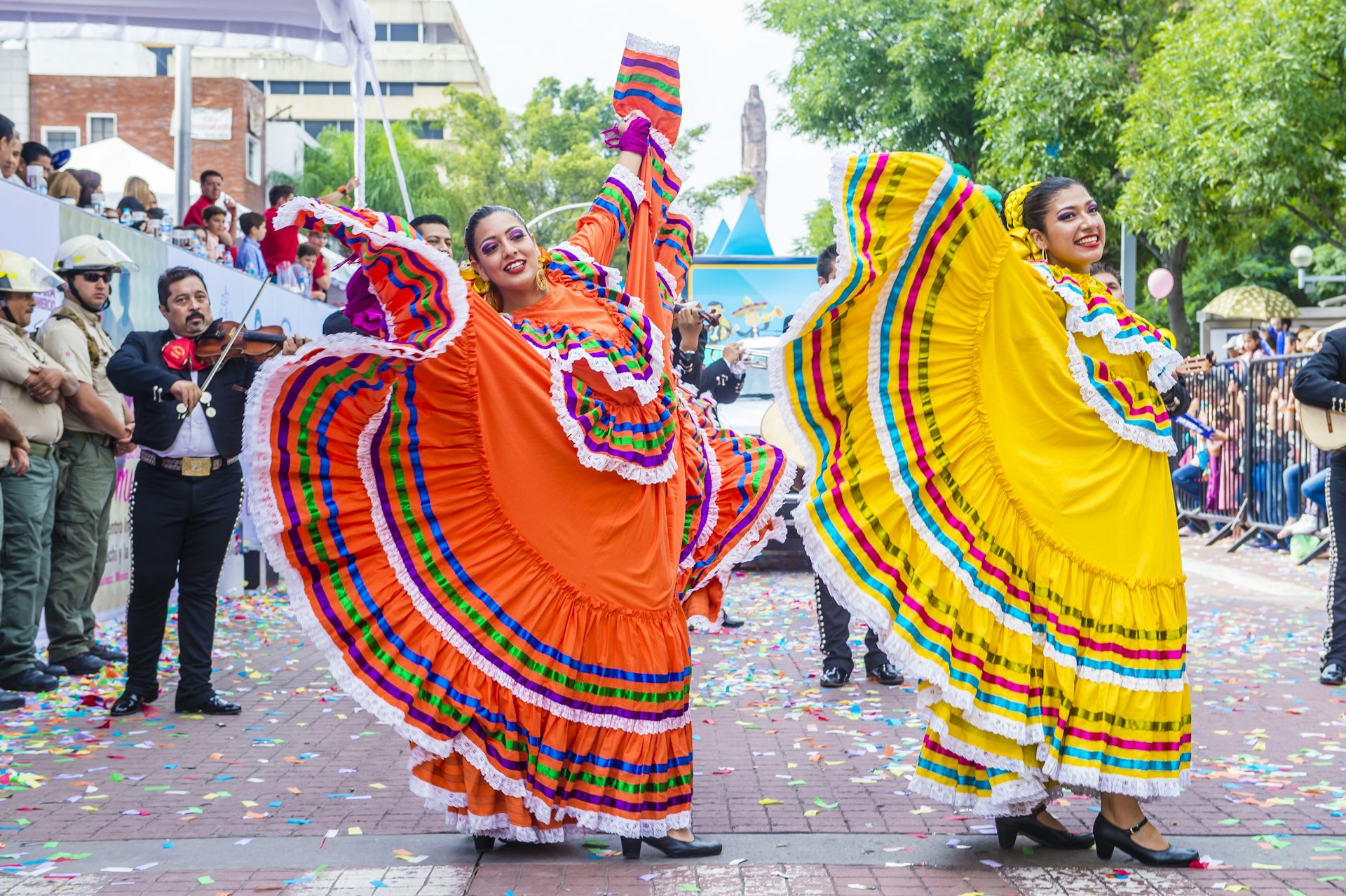 Two dancers wave the long skirts of their tradition dresses as they take part in a parade