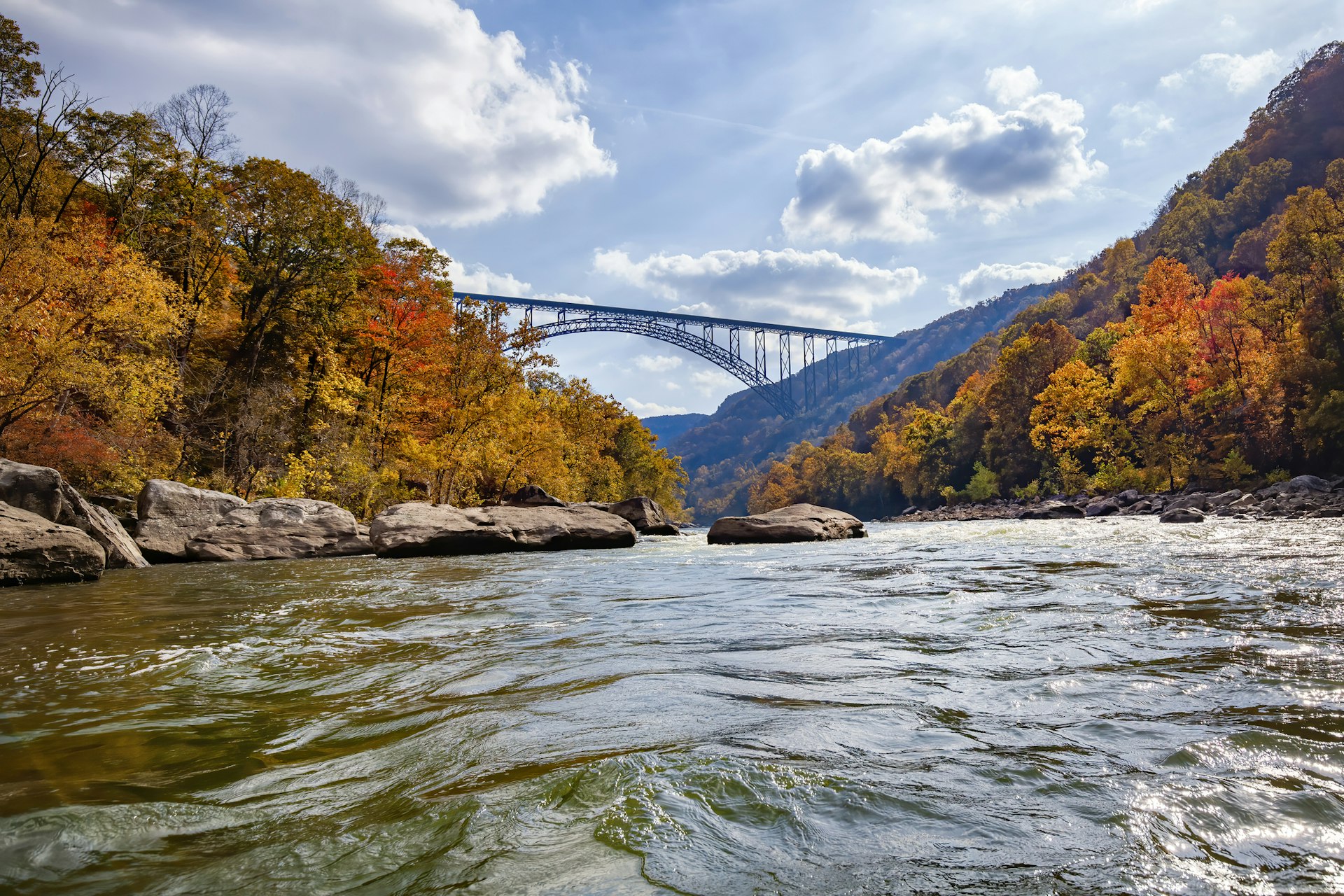 Autumn Colors in West Virginia, a suspension bridge hangs over the New River Gorge with colorful trees on either side of the river