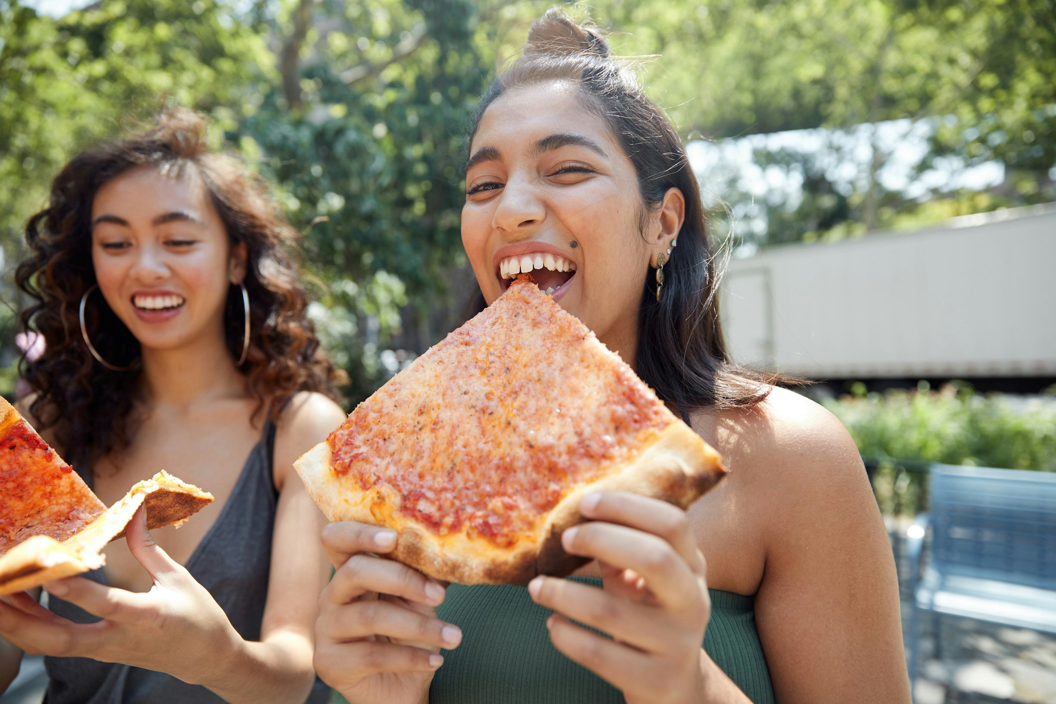 Young females hanging out in city eating pizza