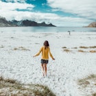 Rear image of young woman walking alone in a remote beach in Norway