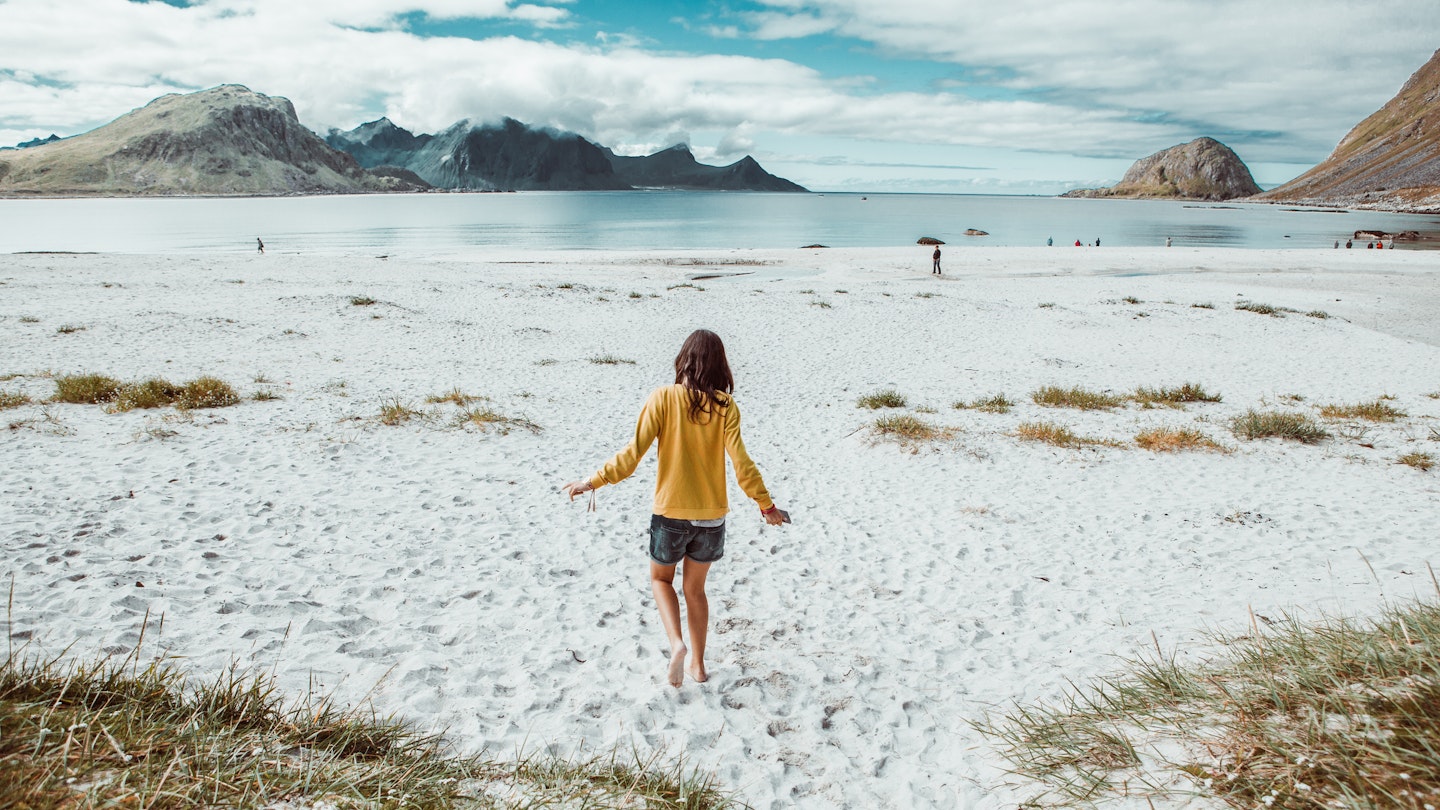 Rear image of young woman walking alone in a remote beach in Norway