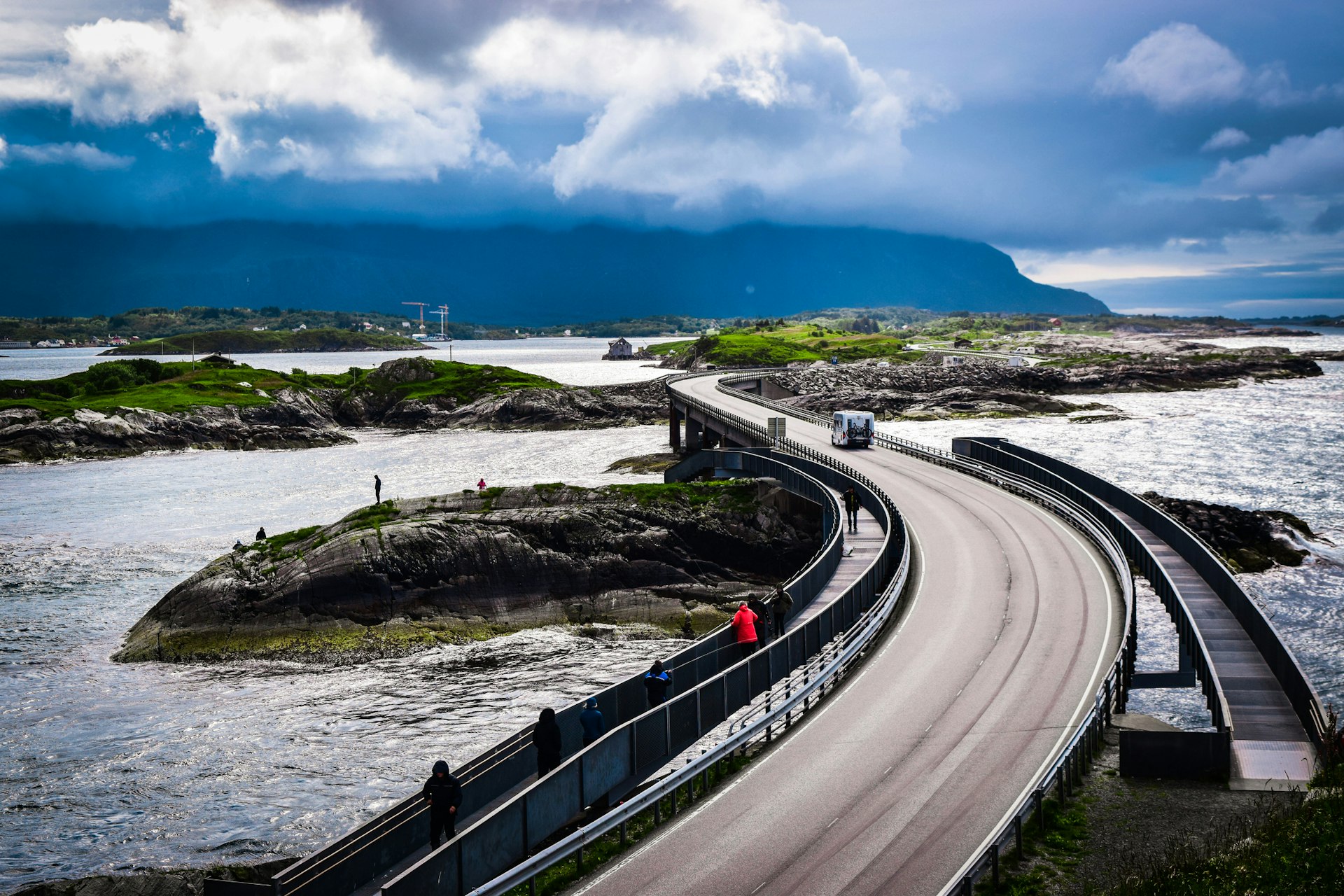 A camper van drives along a road bridge connecting islands in wet weather conditions