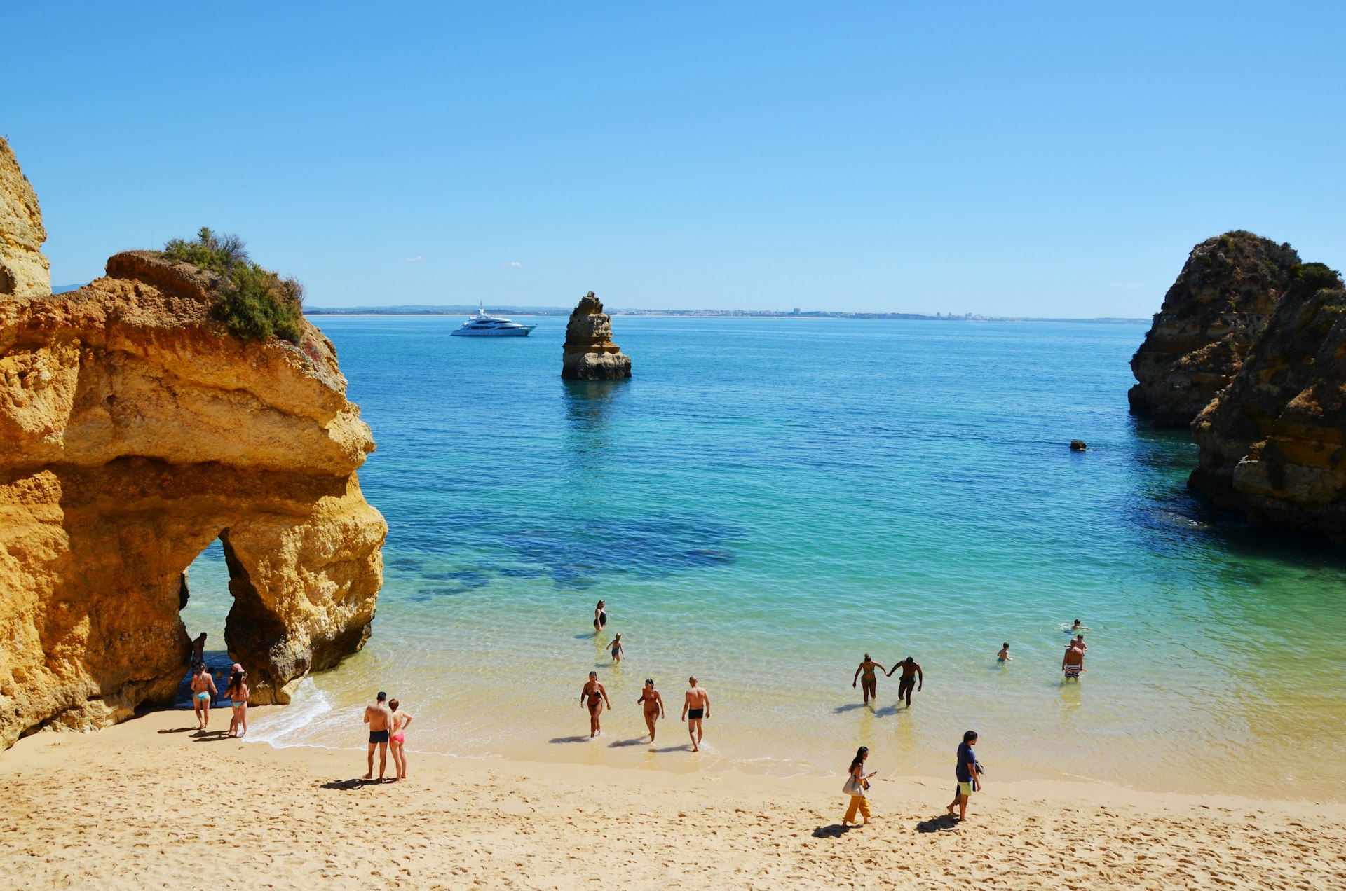 People wade into the water at scenic Camilo Beach (Praia do Camilo) in the Algarve, Portugal, Europe
