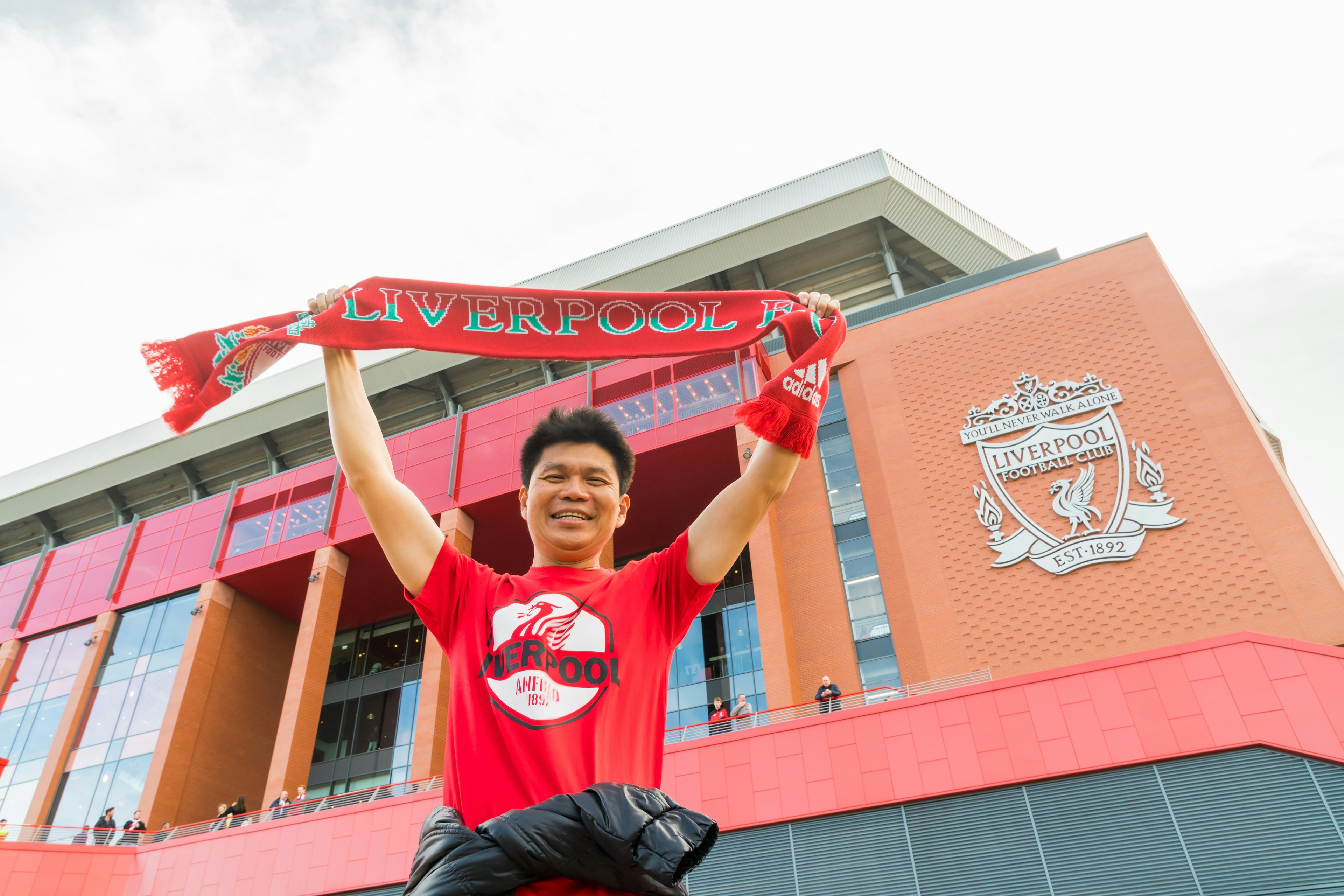 A Liverpool football fan holds up a banner in support of the team outside Anfield Stadium