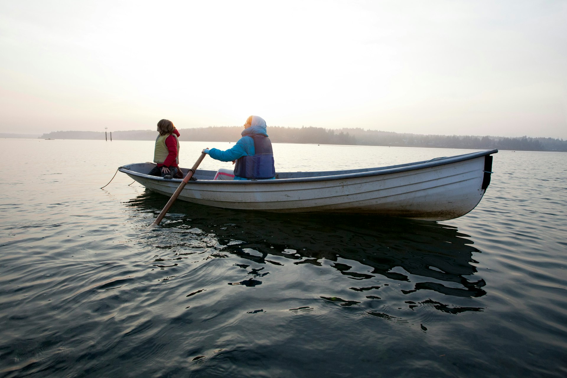 A woman and a Child In A Rowboat At Sunset