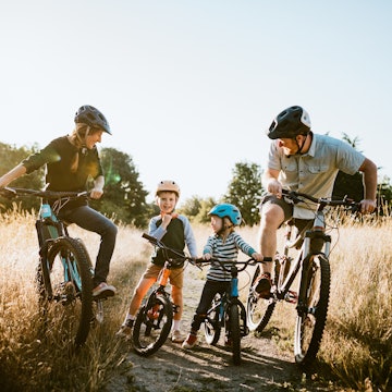 A father and mother ride mountain bikes together with their two small children. A fun way to spend time together and exercise while on vacation in the Seattle, Washington area.