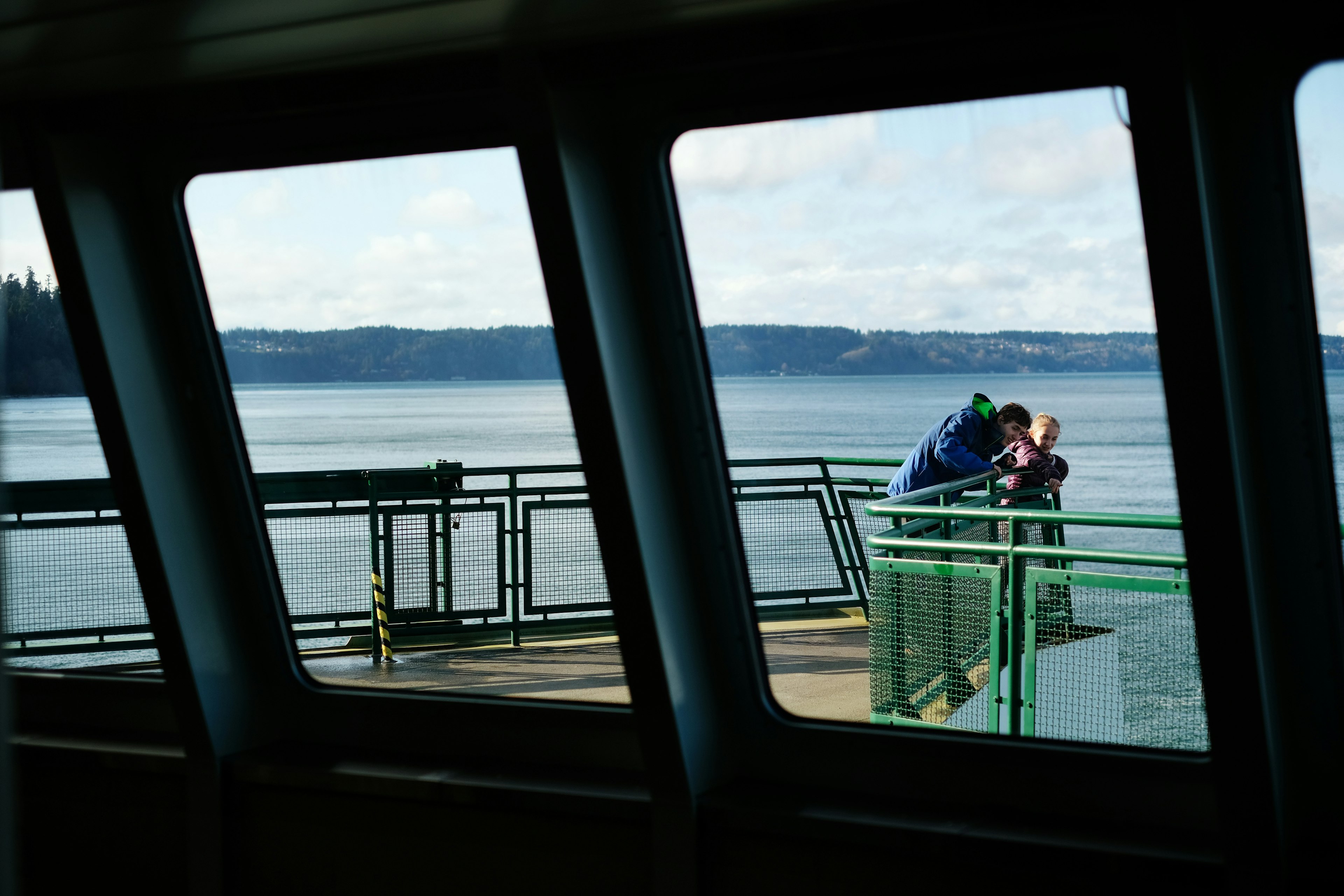 Two siblings stand on the deck of a passenger ferry as it travels through Puget Sound, Seattle