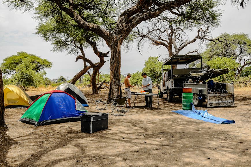 two travelers prepare lunch after preparing the tent camp at Chobe National Park in Botswana
