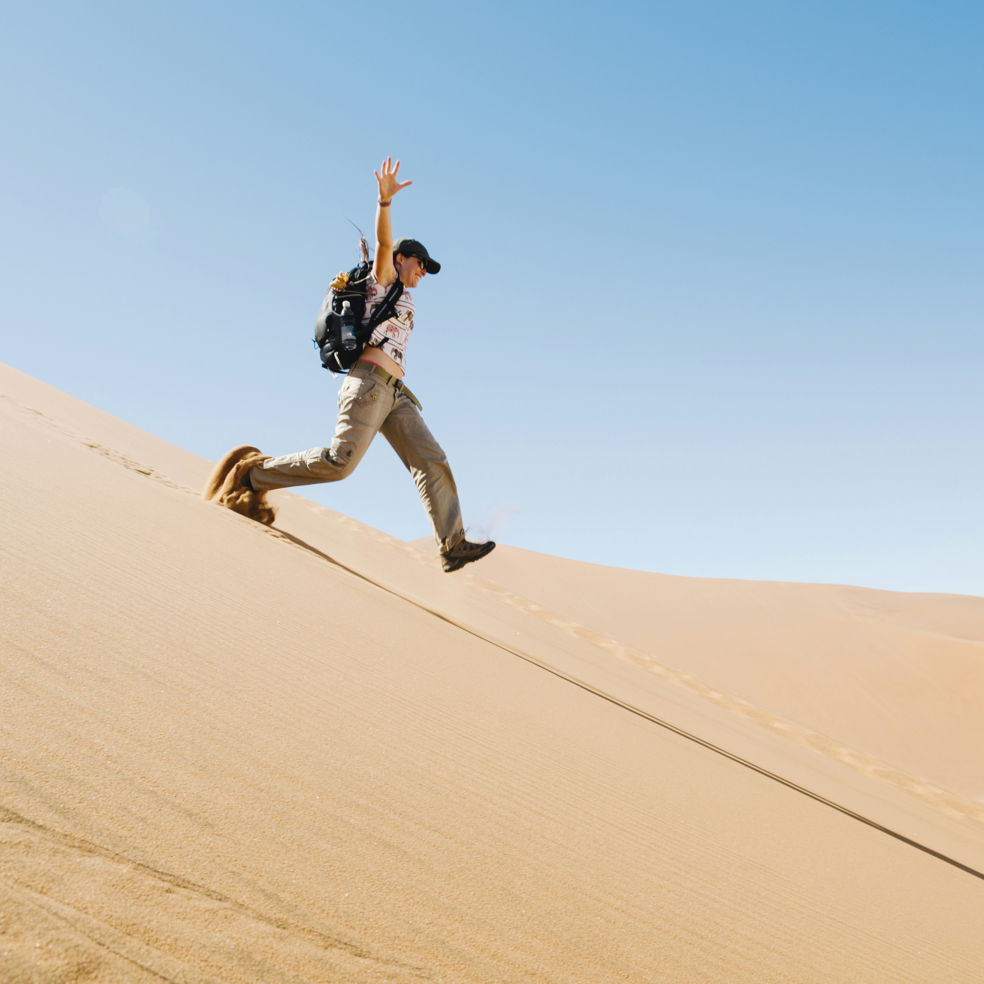 Namibia, Namib Desert, woman running down a dune