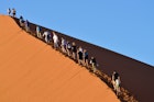 SOSSUSVLEI, NAMIBIA - JAN 29, 2016: Tourists climb Dune No.45 in a year that was declared as a drought year by the government in Namibia, Africa; Shutterstock ID 375359188; your: Sloane Tucker; gl: 65050; netsuite: Online Editorial; full: Namibia National Parks Article