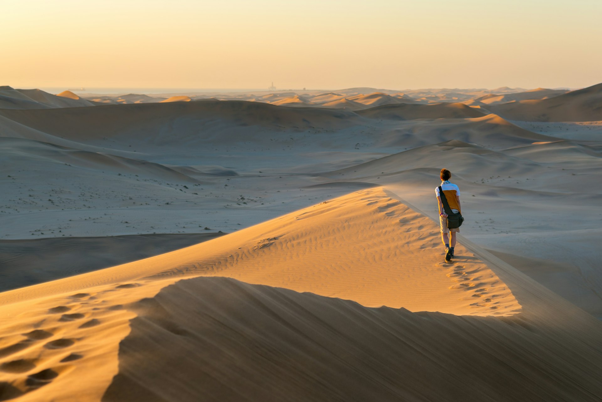 A tourist walks on the scenic dunes of Sossusvlei, Namib desert, Namib-Naukluft National Park, Namibia, Africa