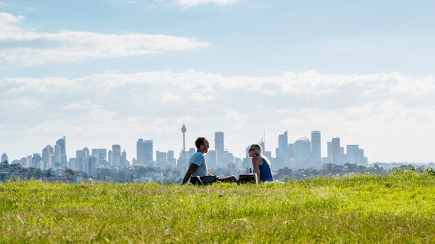 Couple Sitting On Field with Sydney skyline in the background