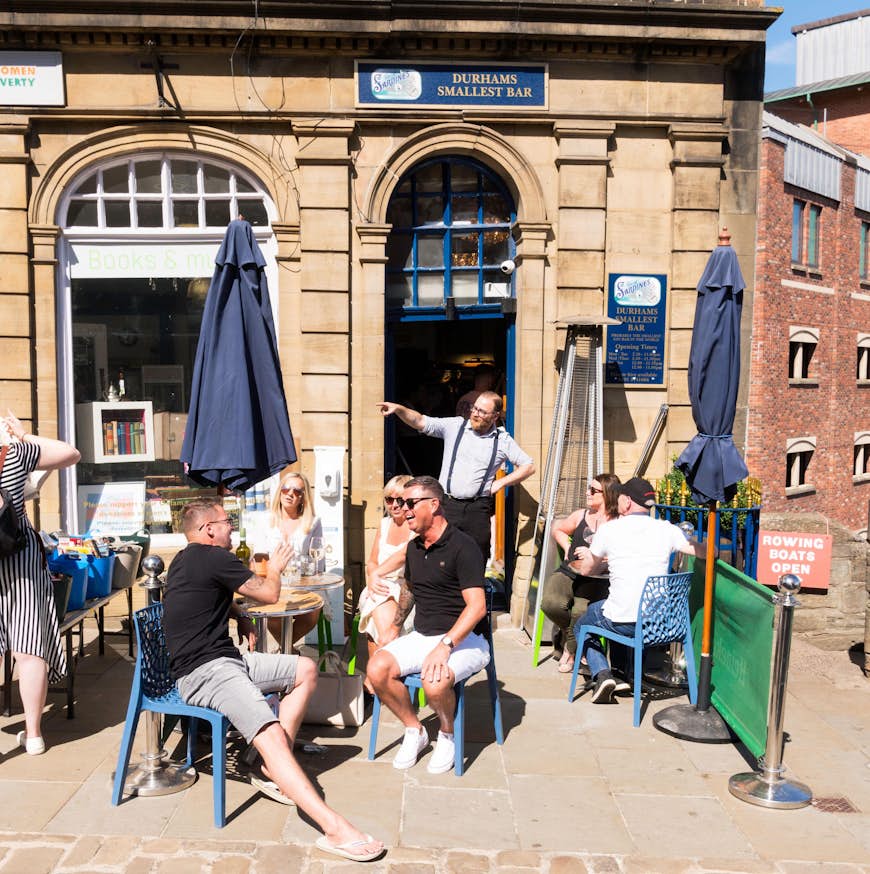 Människor som sitter och dricker utanför Durhams minsta bar, Tin of Sardines, på Elvet Bridge, Durham City, England, Storbritannien