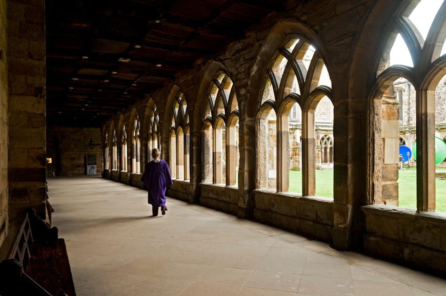 En person går nerför en korridor i klostret i Durham Cathedral, Durham, England, Storbritannien