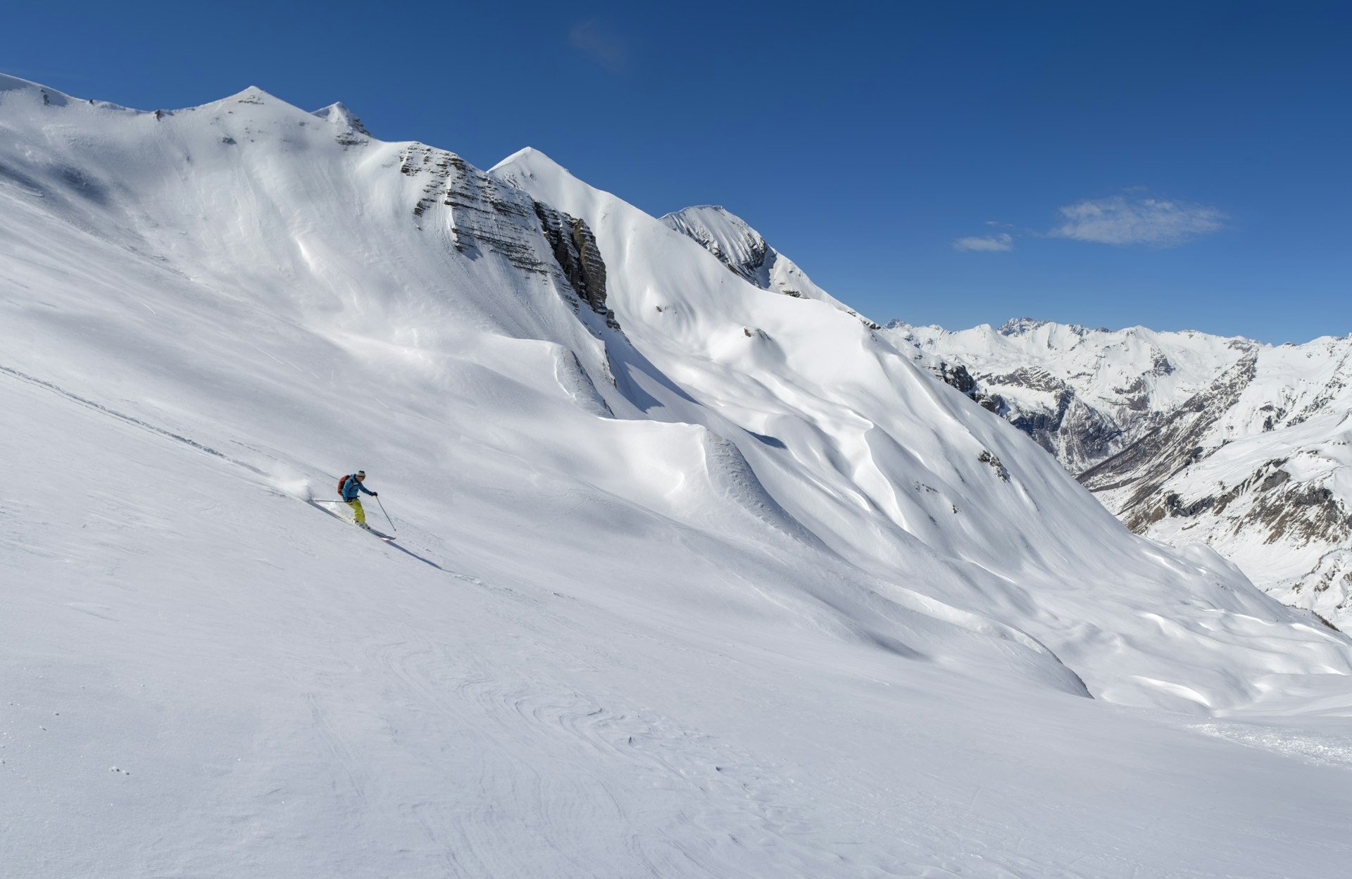 A skier speeds down a snowy slope in the Hautes Alpes of Ecrins National Park in France