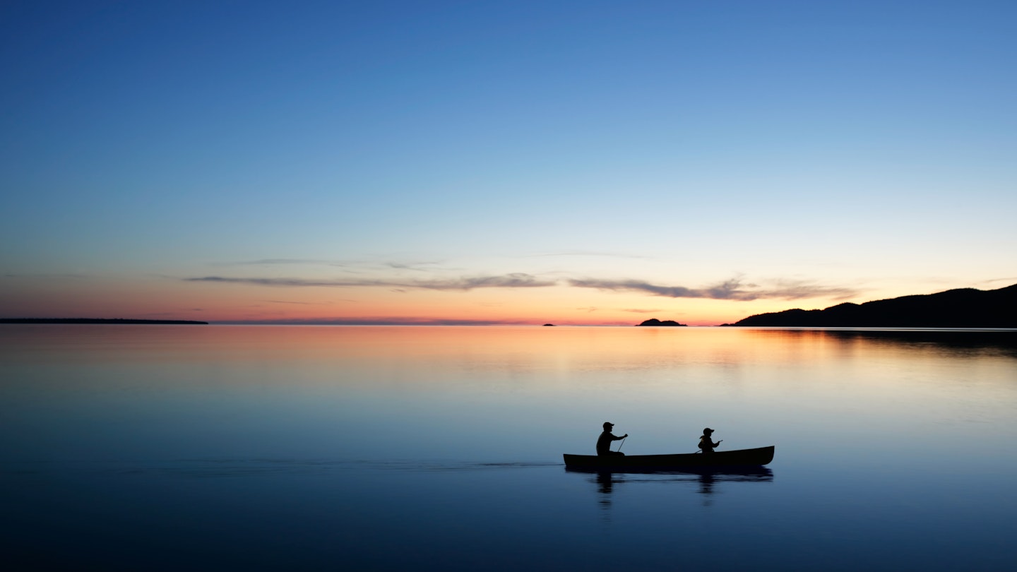 Man and son canoeing on Lake Michigan at dusk.