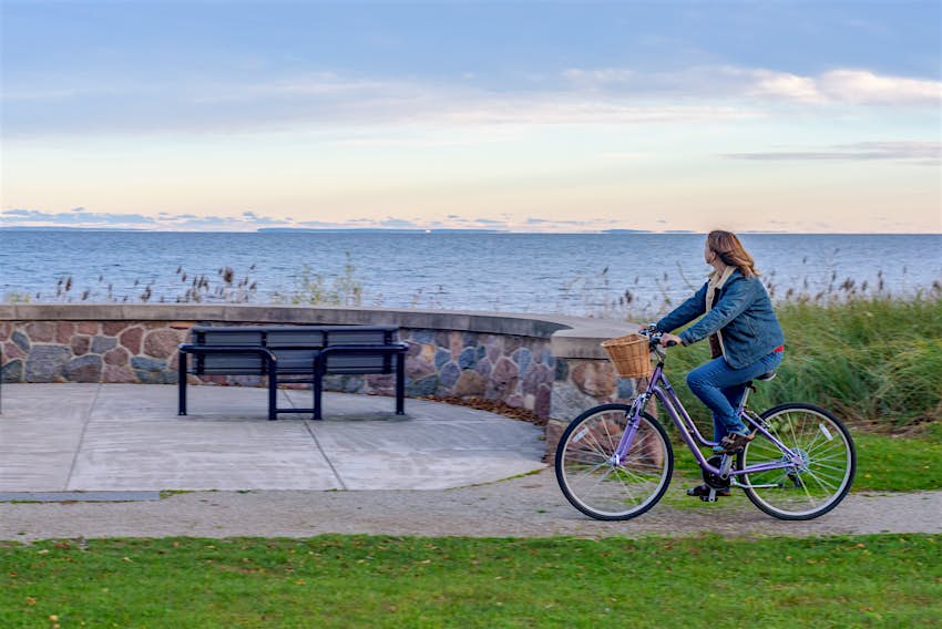 Woman Riding Bicycle At Beach Against Sky During Sunset in Michigan
