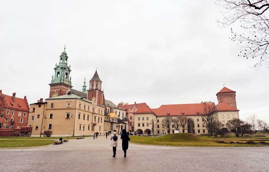 Two tourists standing outside and looking up at Wawel Royal Castle 