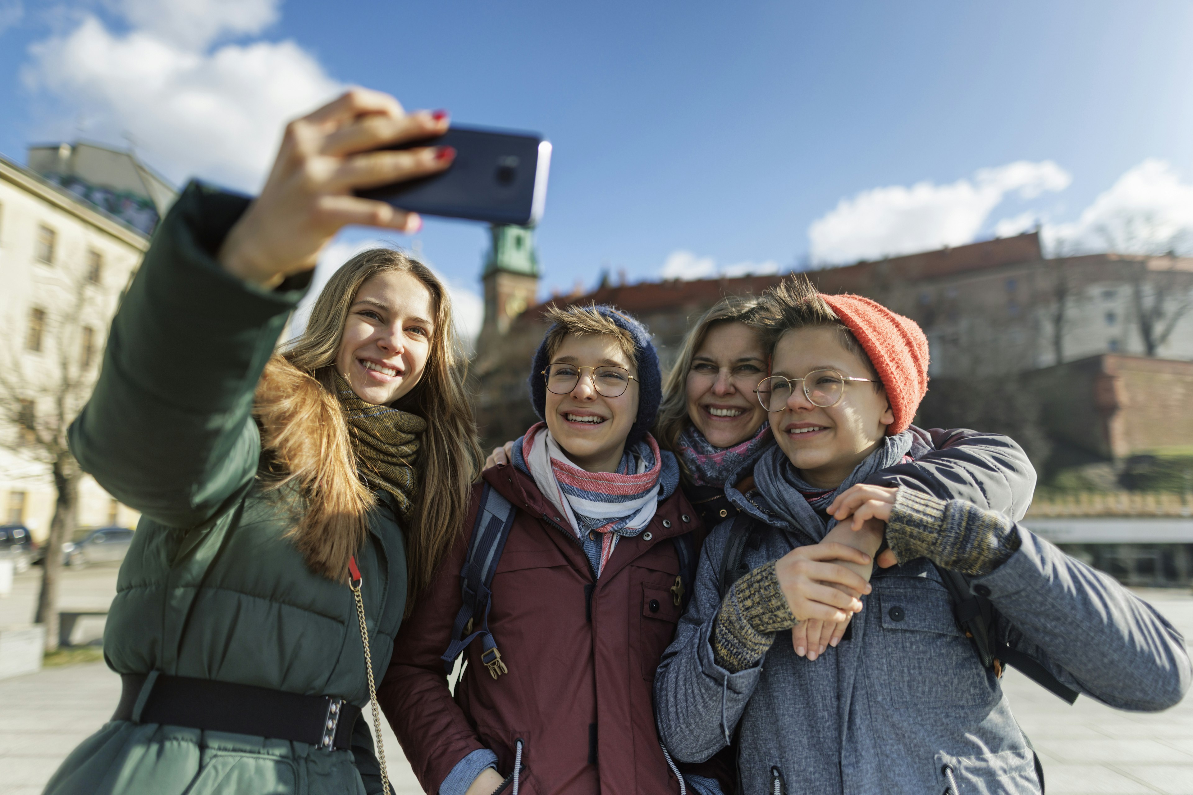 Family sightseeing city of Cracow, Poland on an off-season winter day. Family is taking photos in the square near the Wawel castle