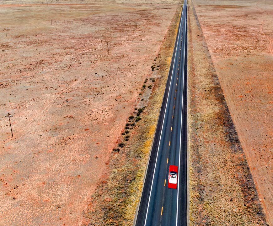 Red car driving down Route 66 in Arizona surrounded by desert