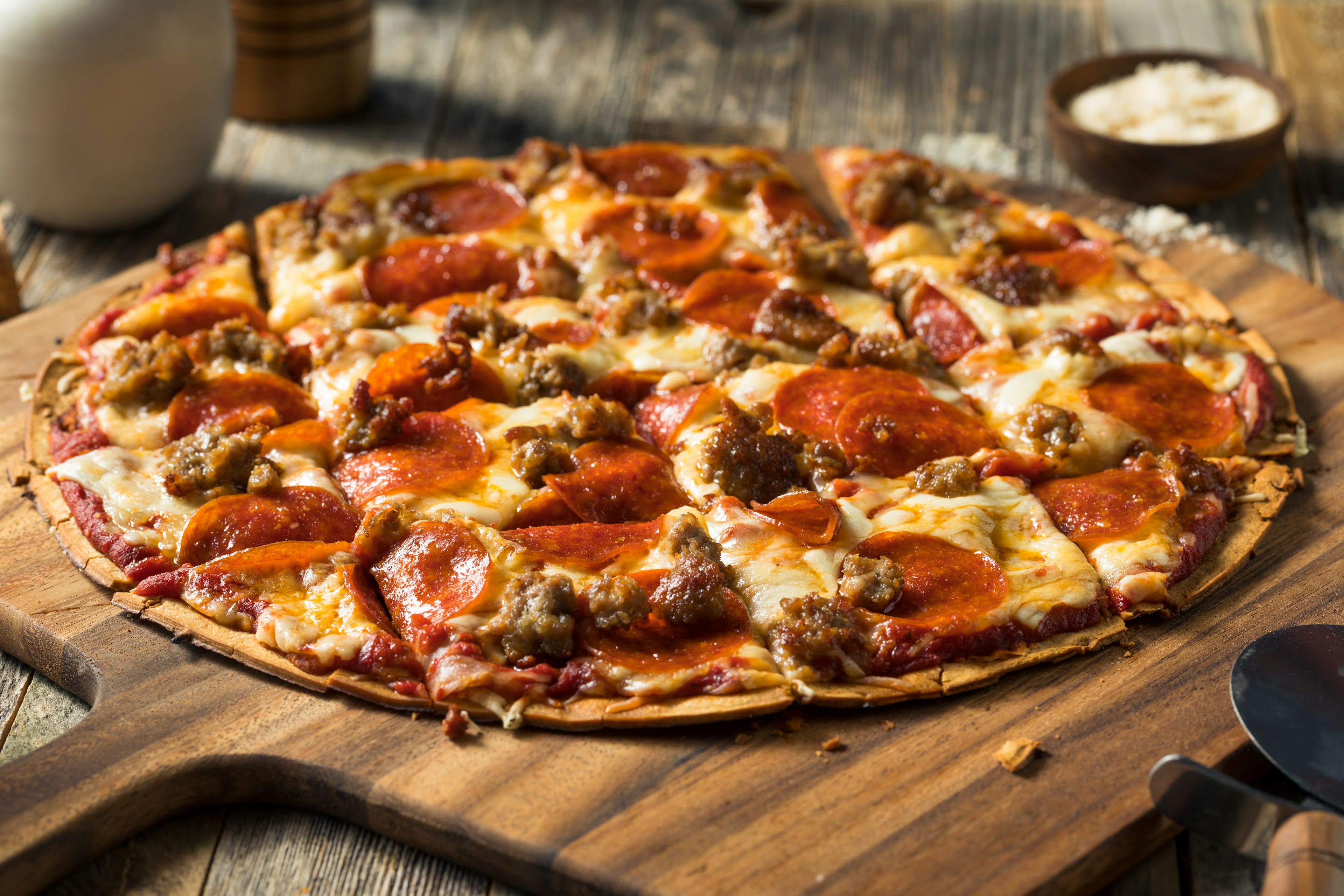 A round pizza with meaty toppings that has been cut into squares