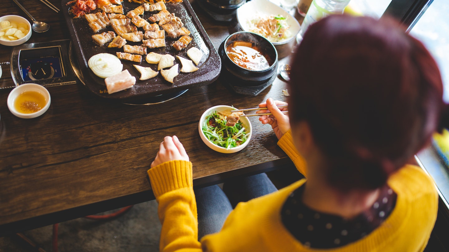 Rear View Of Caucasian Young Woman Tasting New Korean Meals