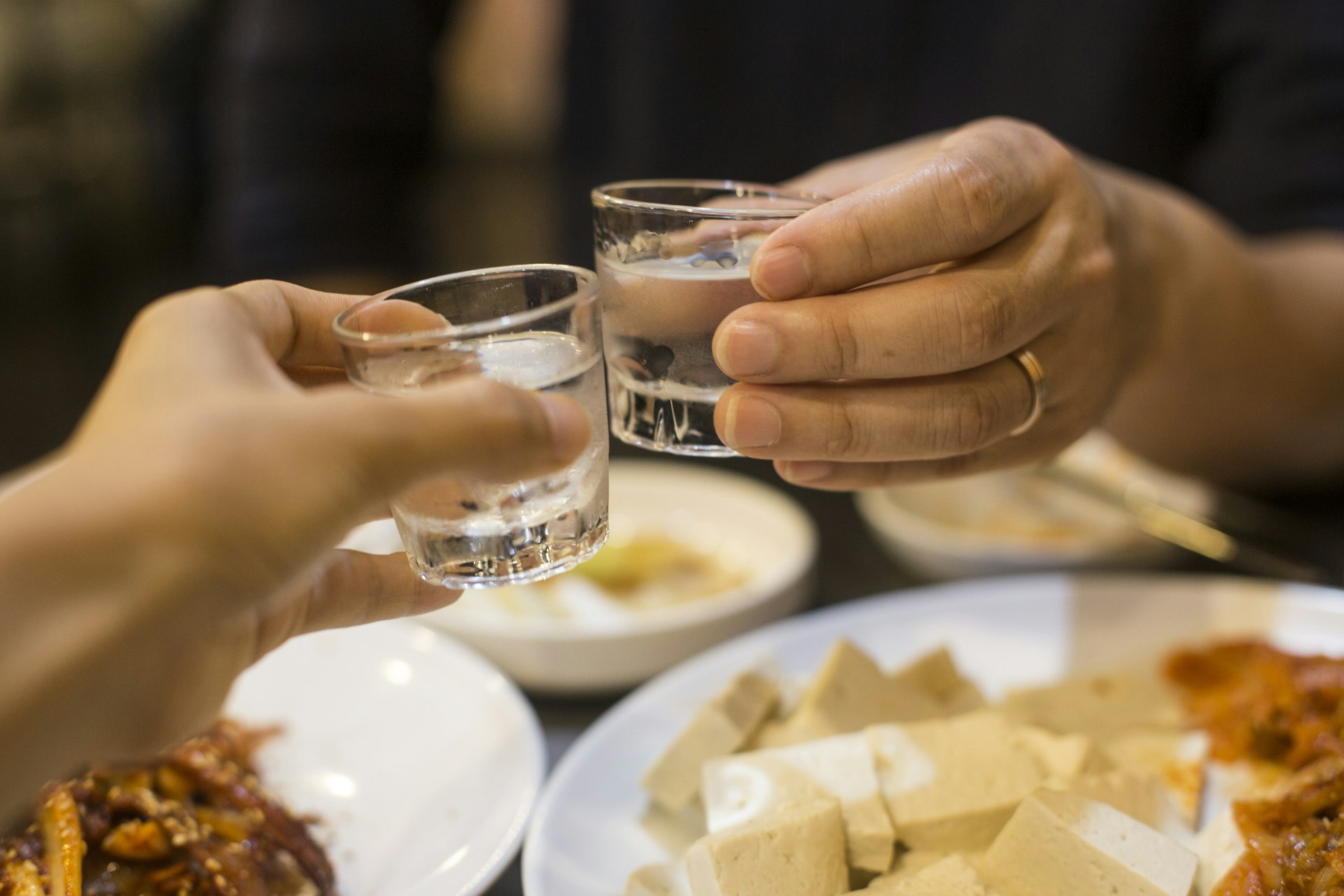 Two people toast with soju at a restaurant in South Korea, Asia