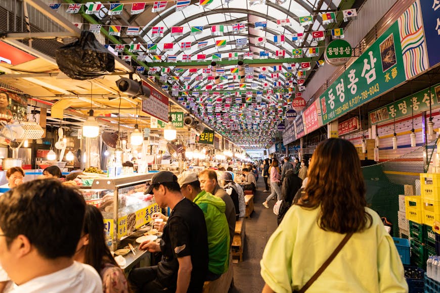 People walks by vendors in stalls at Gwangjang, a food market in Seoul, South Korea