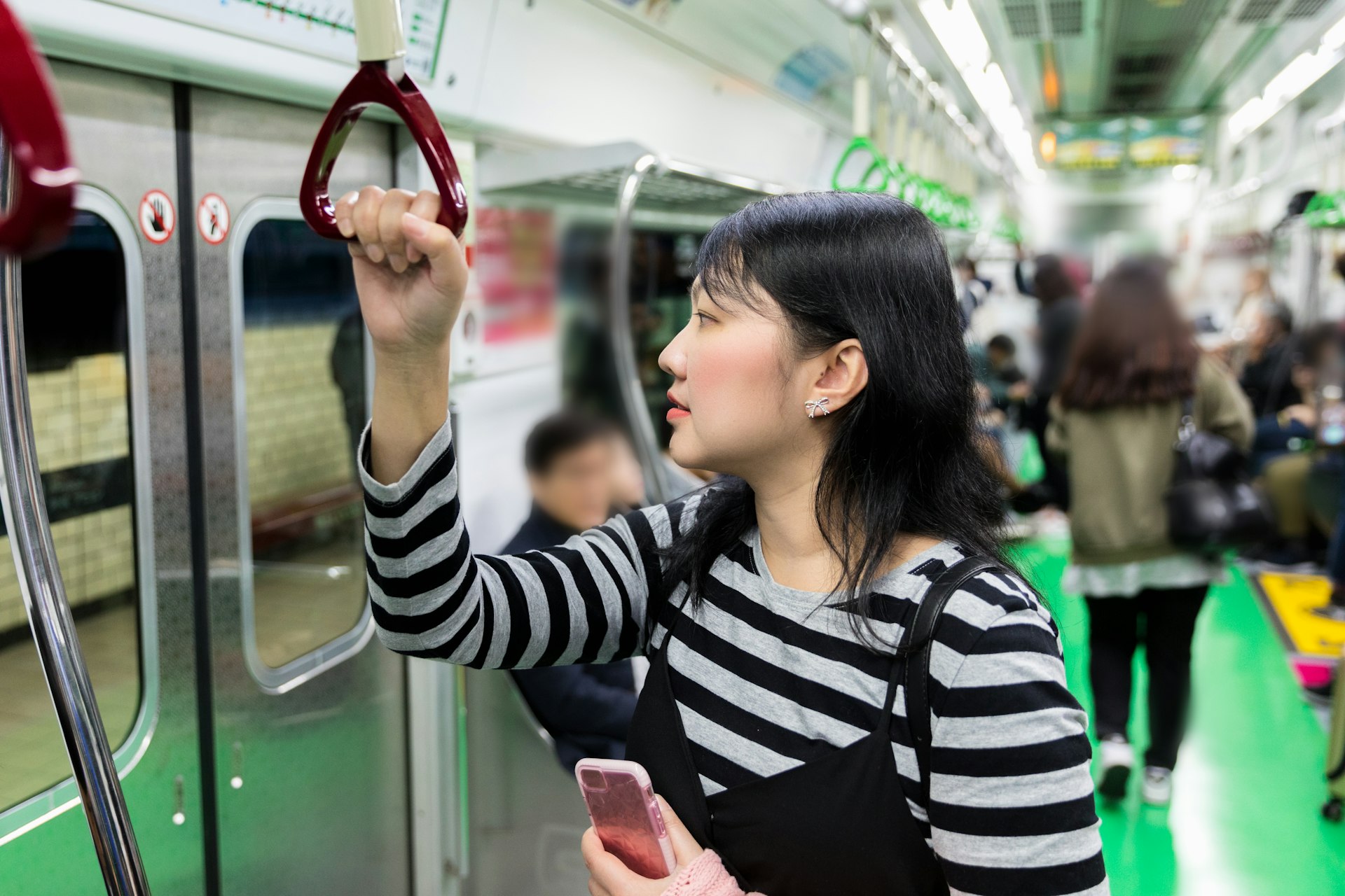 A woman holds the strap while standing on the Seoul underground