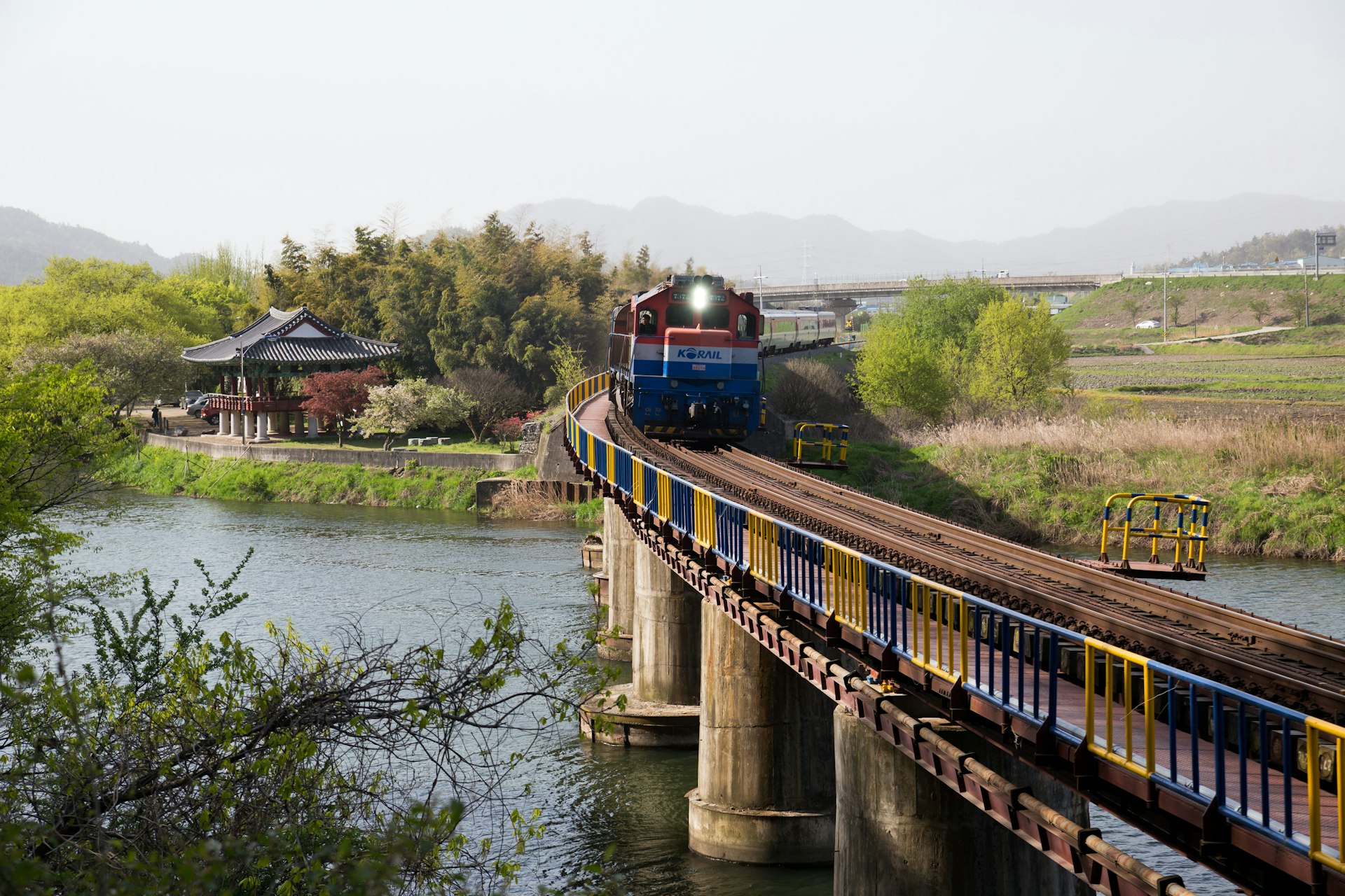 Morning view of Mugunghwa Train moving on railroad bridge on Jiseokcheon Stream with Yeongbyeokjeong Pavilion in the background